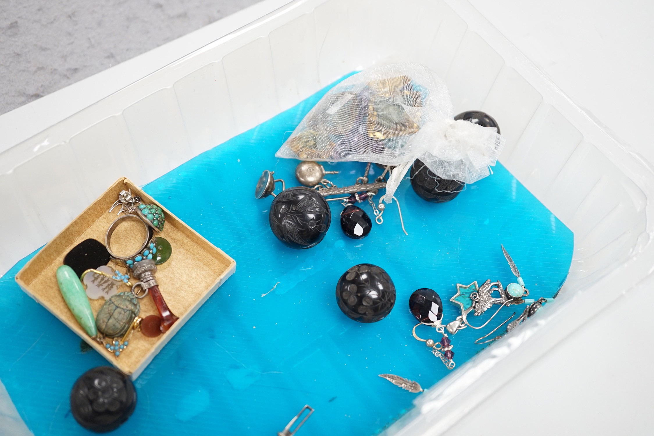A silver charm bracelet hung with fifty assorted charms and a group of assorted jewellery including enamelled locket, Victorian agate fob seal carved with a bird, scarab pendant, coloured paste set brooch, 925 triple dol